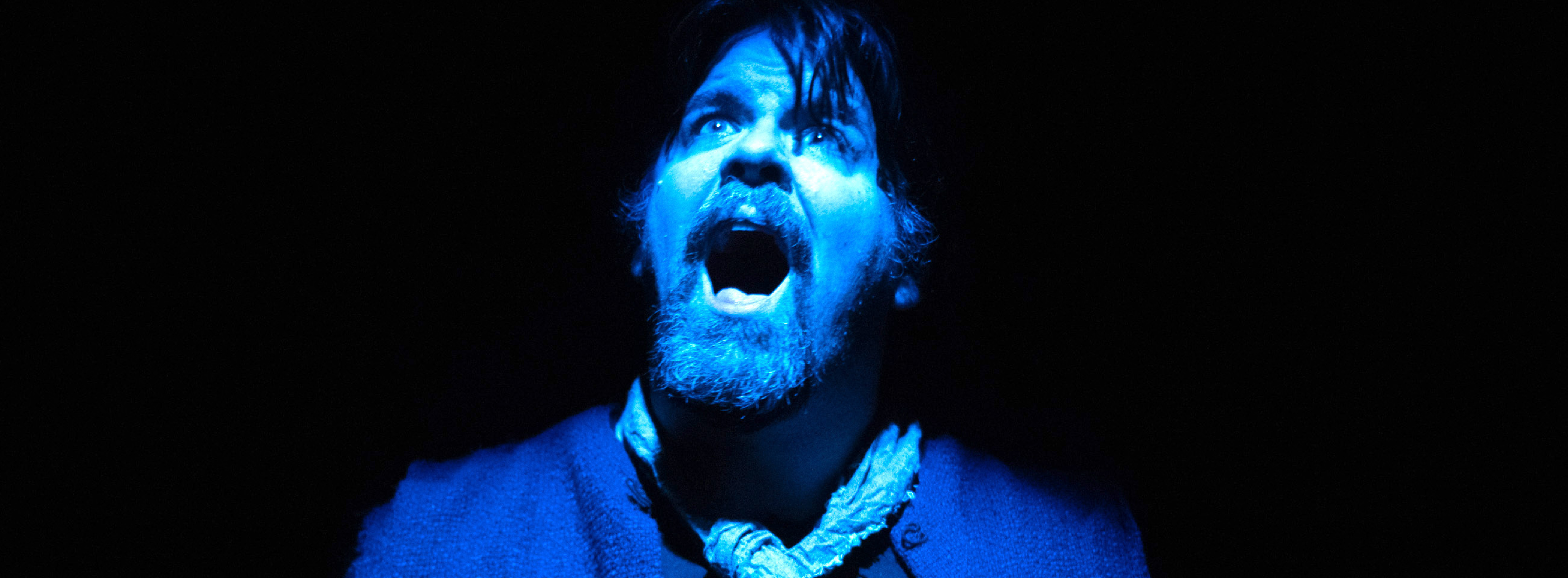 An actor screams at the sky bathed in blue light