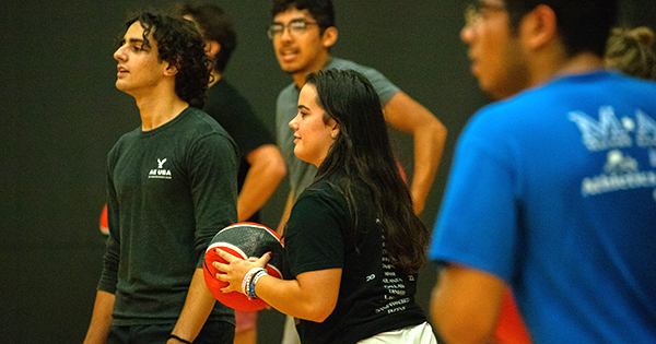 students playing dodgeball highlighting the girl in the center holding the ball