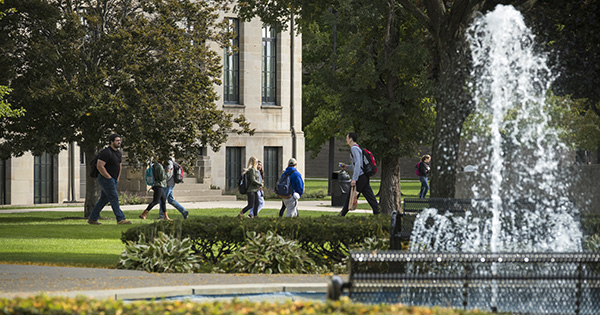 students walking to class viewable just beyond the fountain.